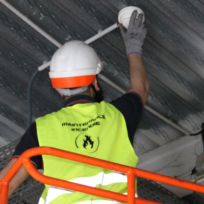 Photo d'un de nos mainteneurs, en train de vérifier un détecteur de fumée.